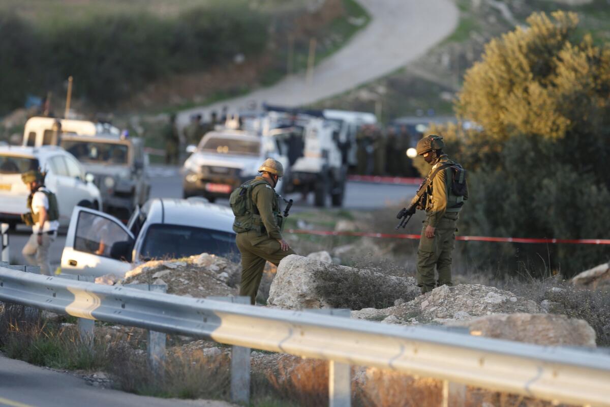 Israeli soldiers stand at the scene of a shooting attack that killed an Israeli father and son near the West Bank city of Hebron on Friday.