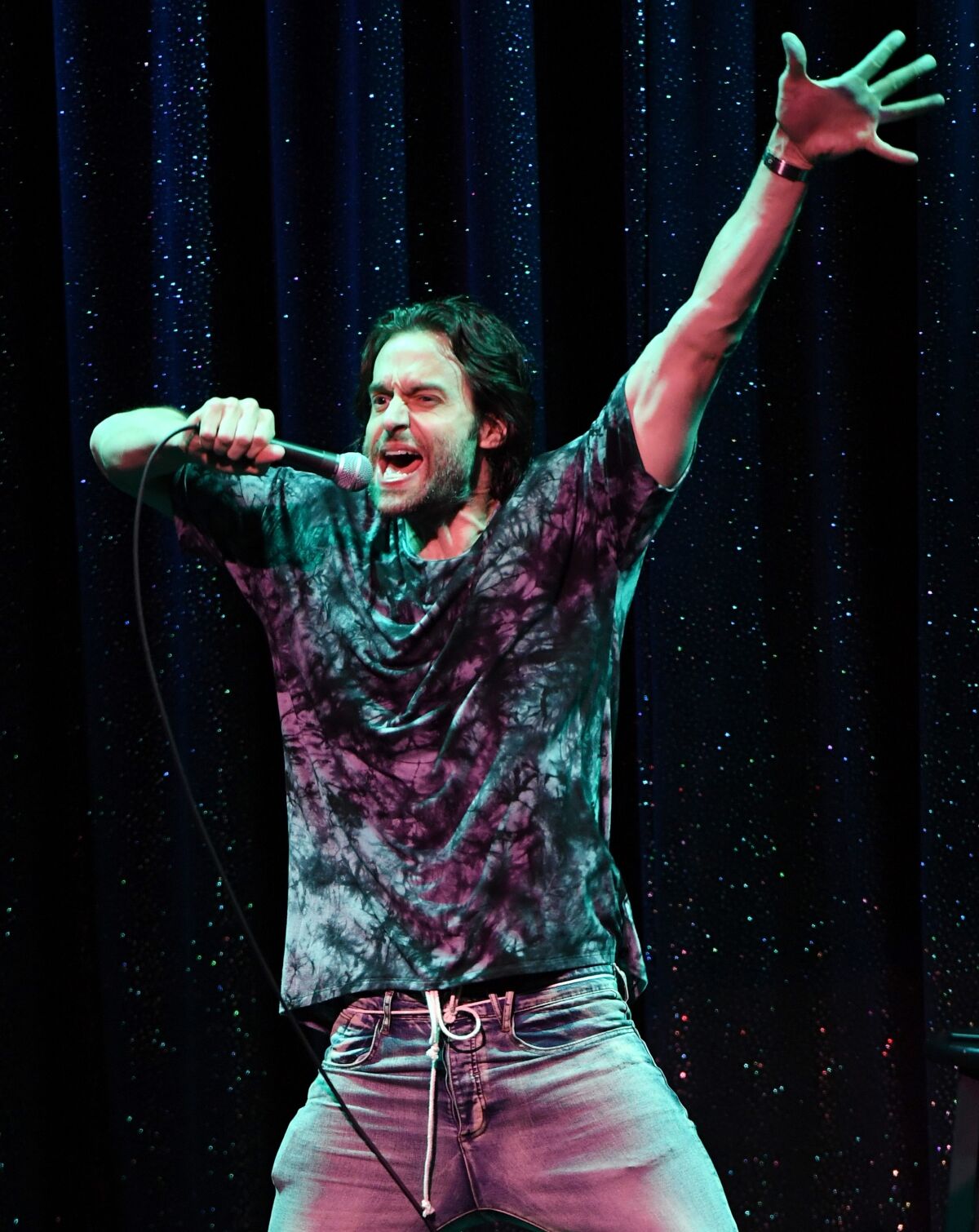 Chris D'Elia onstage holding a microphone