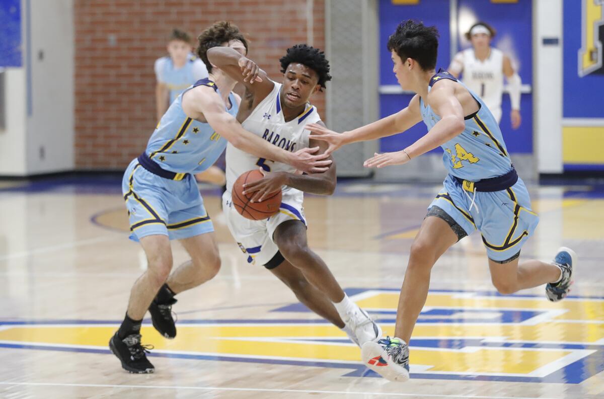 Fountain Valley's Jeremiah Davis tries to run between two Marina defenders and is fouled in the process on Friday night.
