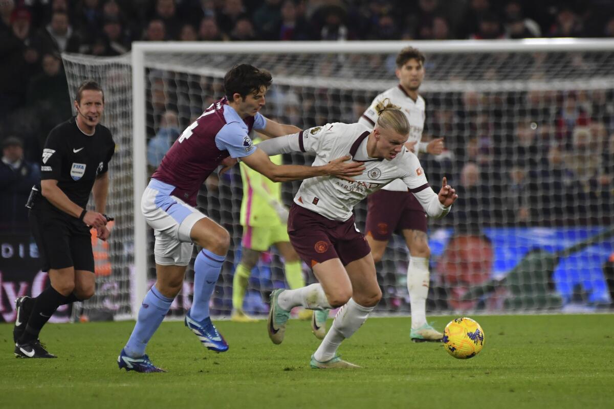 Manchester City's Erling Haaland tries to control the ball while defended by Aston Villa's Pau Torres.