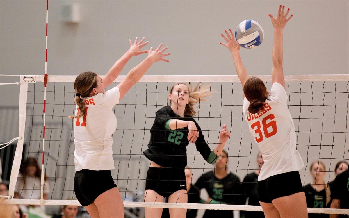 Mira Costa High’s Audrey Flanagan hits through Huntington Beach blockers Haylee LaFontaine and Kylie Leopard on Saturday.