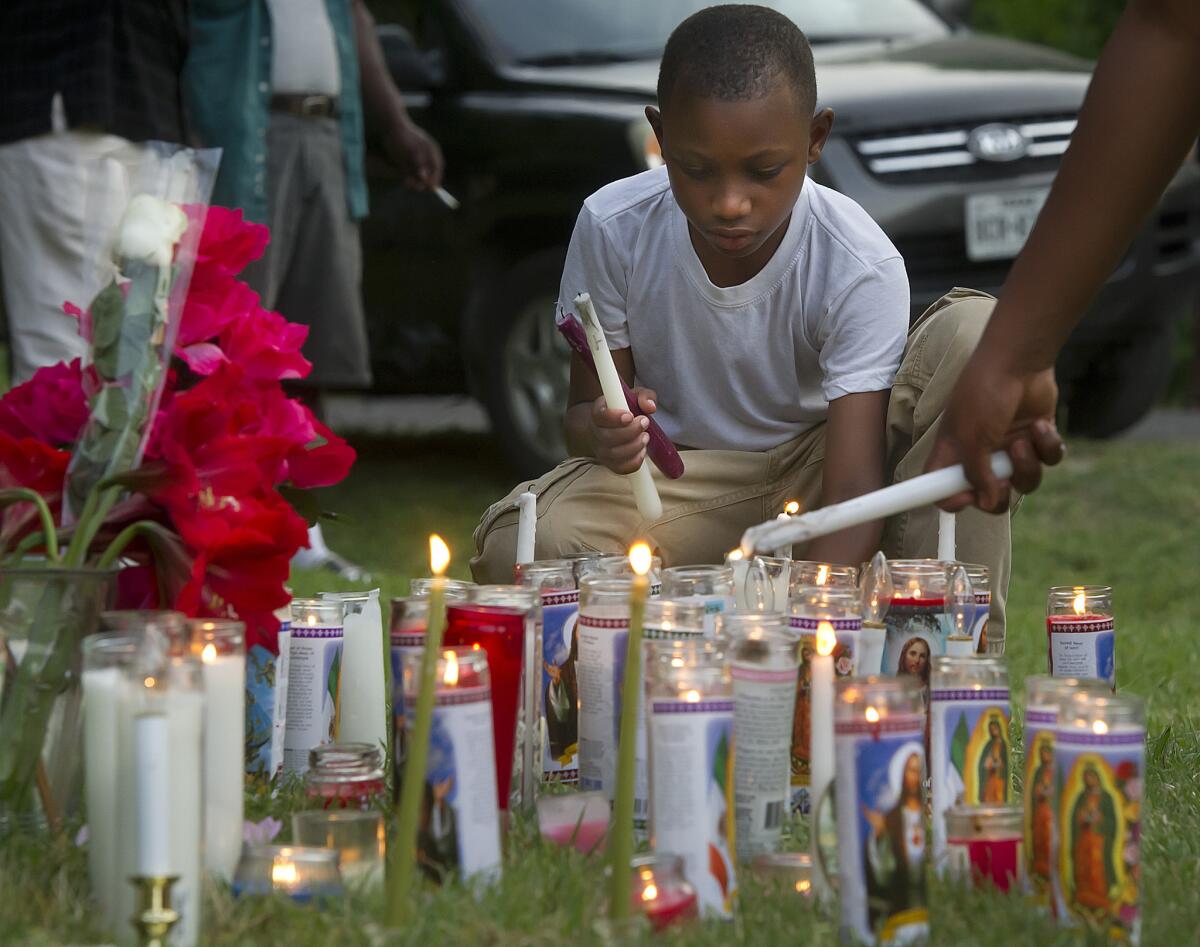 Darrel Brown, 8, lights candles at a makeshift memorial for Pearlie Golden during a vigil at Golden's home Wednesday in Hearne, Texas.