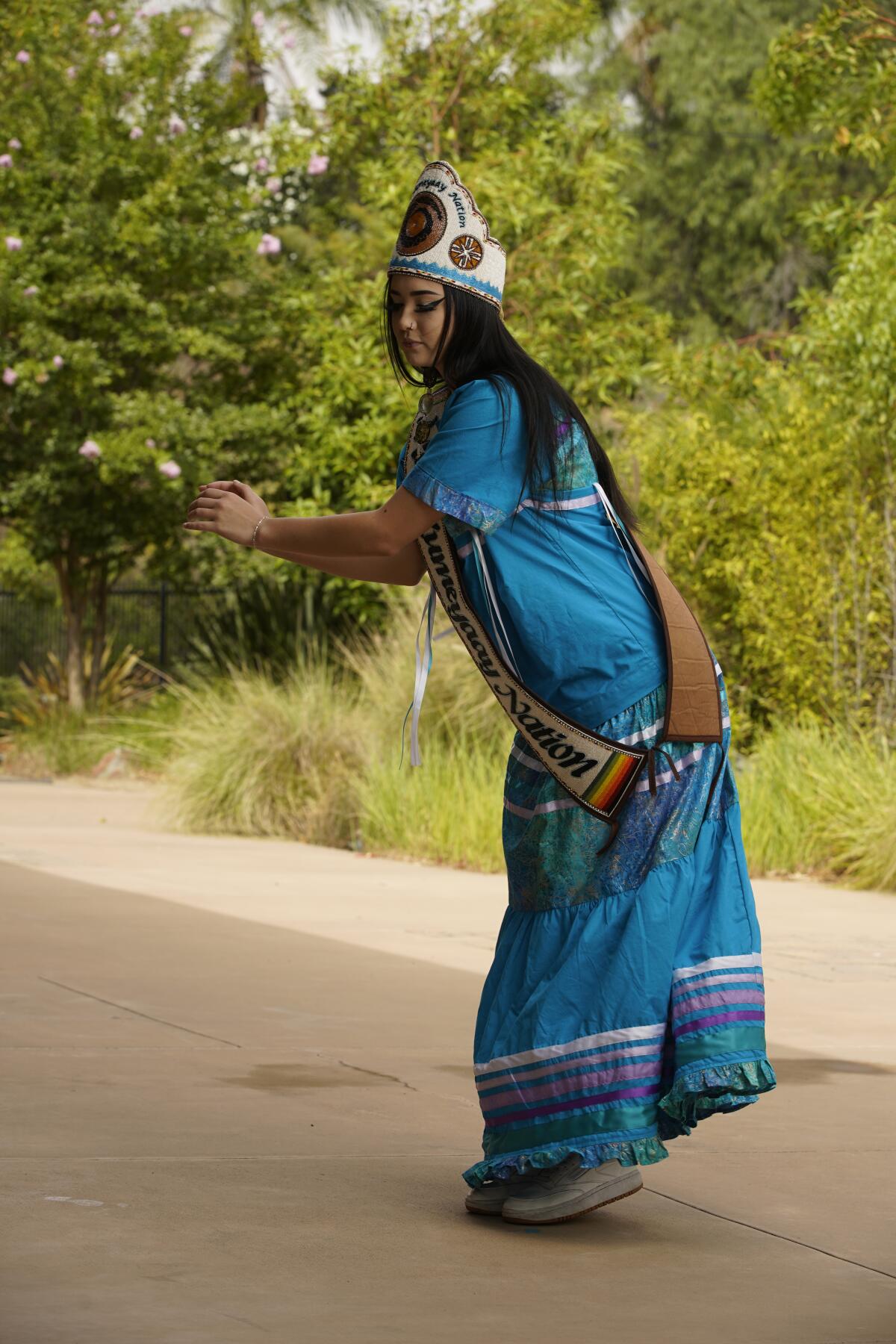a woman in traditional Kumeyaay clothing dances outside