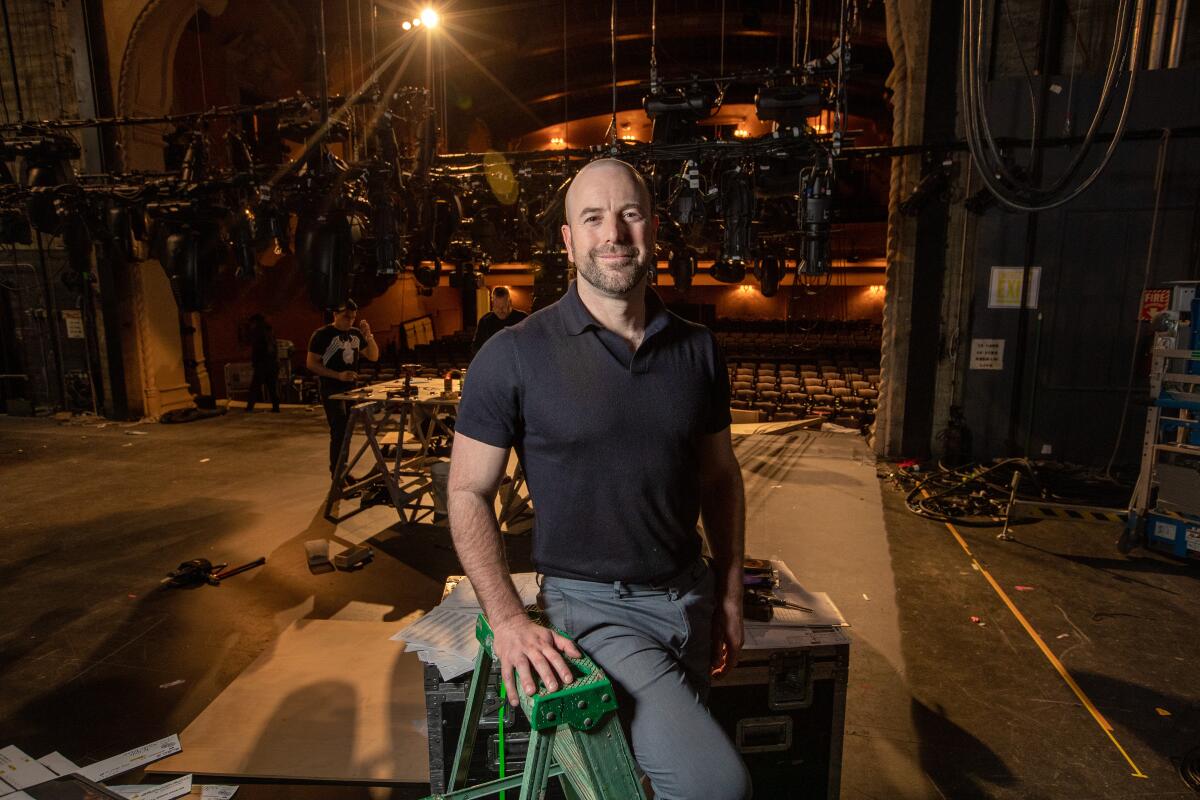 Danny Feldman at the edge of a stage where a set is being installed.