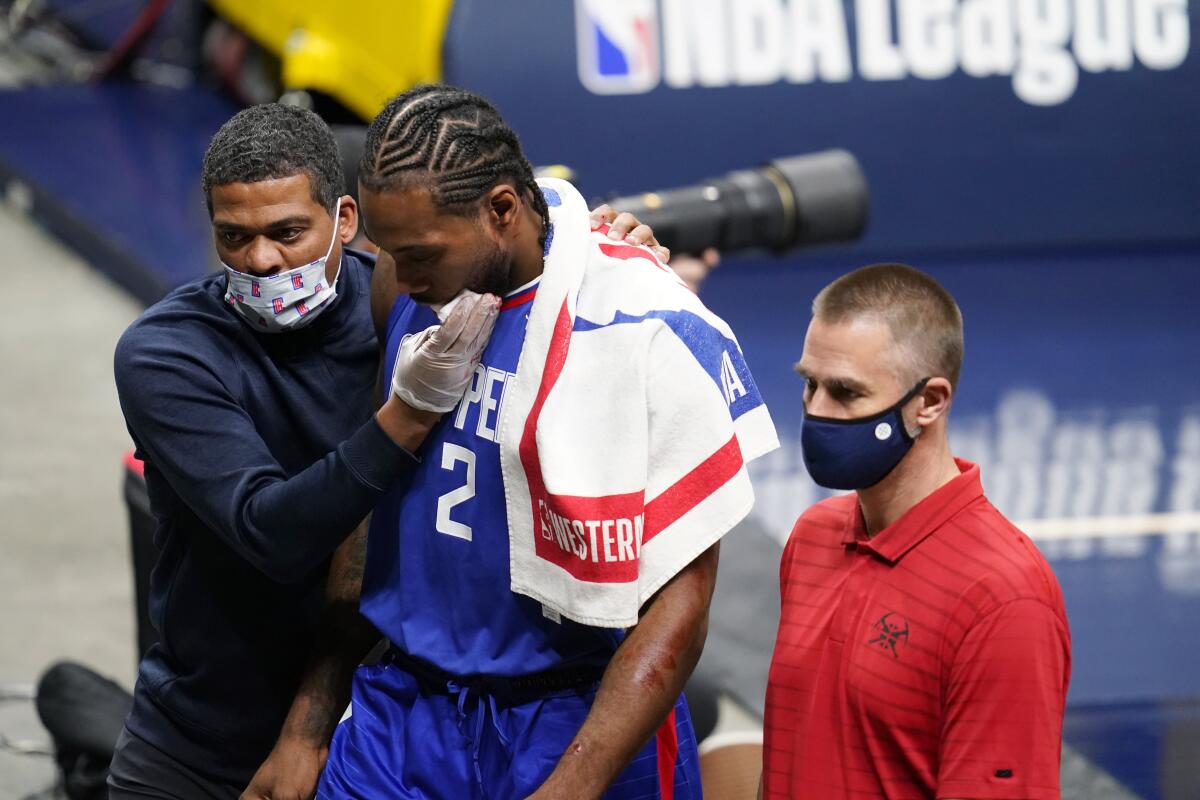 Trainers tend to Clippers forward Kawhi Leonard as he walks off the court.