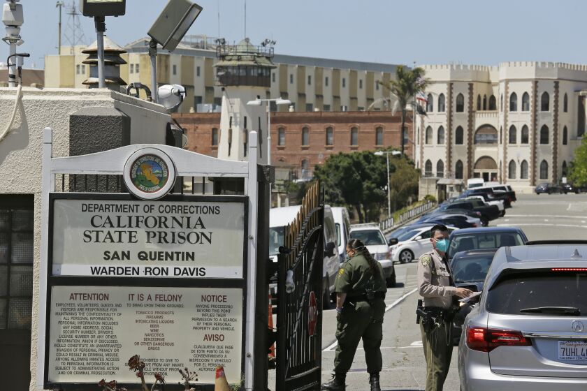 FILE - In this July 9, 2020, file photo, a correctional officer checks a car entering the main gate of San Quentin State Prison in San Quentin, Calif. Two more inmates at San Quentin State Prison near San Francisco died from what appear to be complications of the coronavirus, corrections officials said Monday, Aug. 3, 2020. Two inmates, including a death row inmate, died Sunday at outside hospitals, the California Department of Corrections and Rehabilitation said. (AP Photo/Eric Risberg, File)