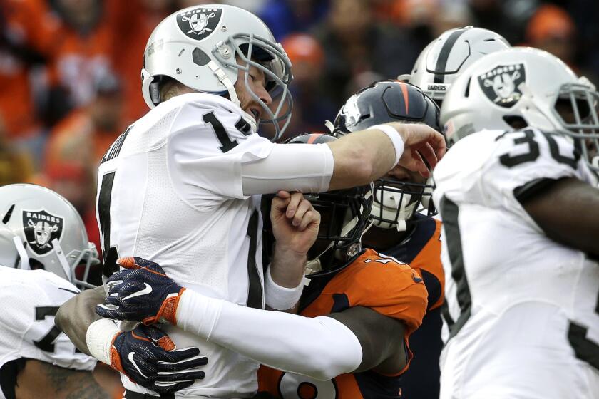 Raiders quarterback Matt McGloin is hit by Broncos linebacker Shaquil Barrett after throwing a pass during the first half Sunday.
