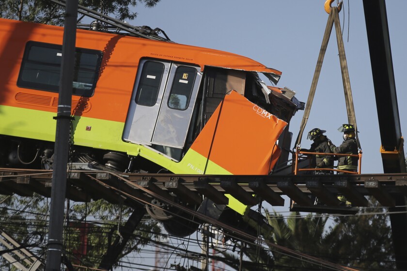 Firefighters work to lower to the ground a subway car dangling from a collapsed elevated section of the metro, in Mexico City, Tuesday, May 4, 2021. The elevated section of Mexico City's metro collapsed late Monday killing at least 23 people and injuring at least 79, city officials said. (AP Photo/Fernando Llano)