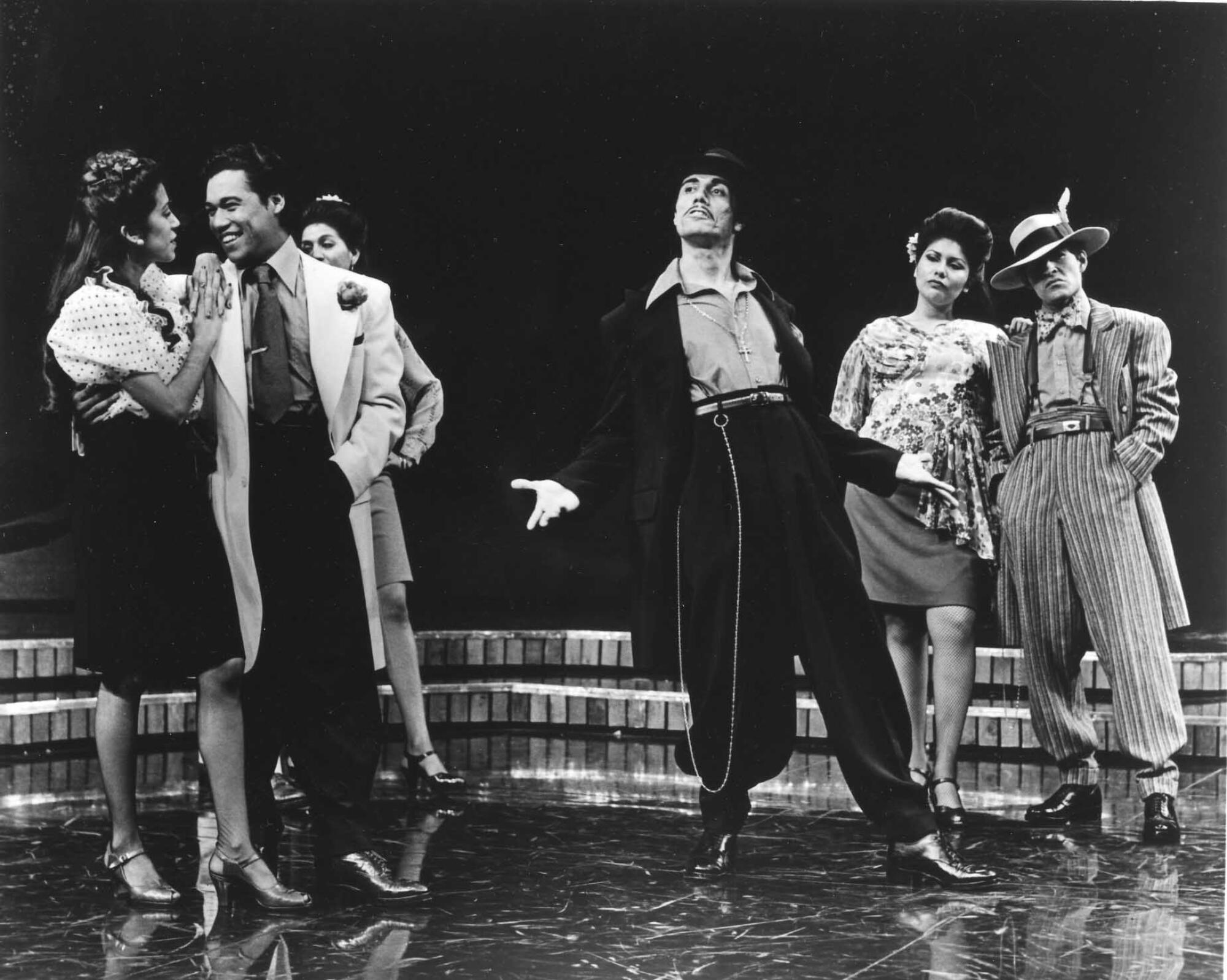 A historic photo shows a group of actors, including Edward James Olmos, dressed as pachucos in zoot suits on stage