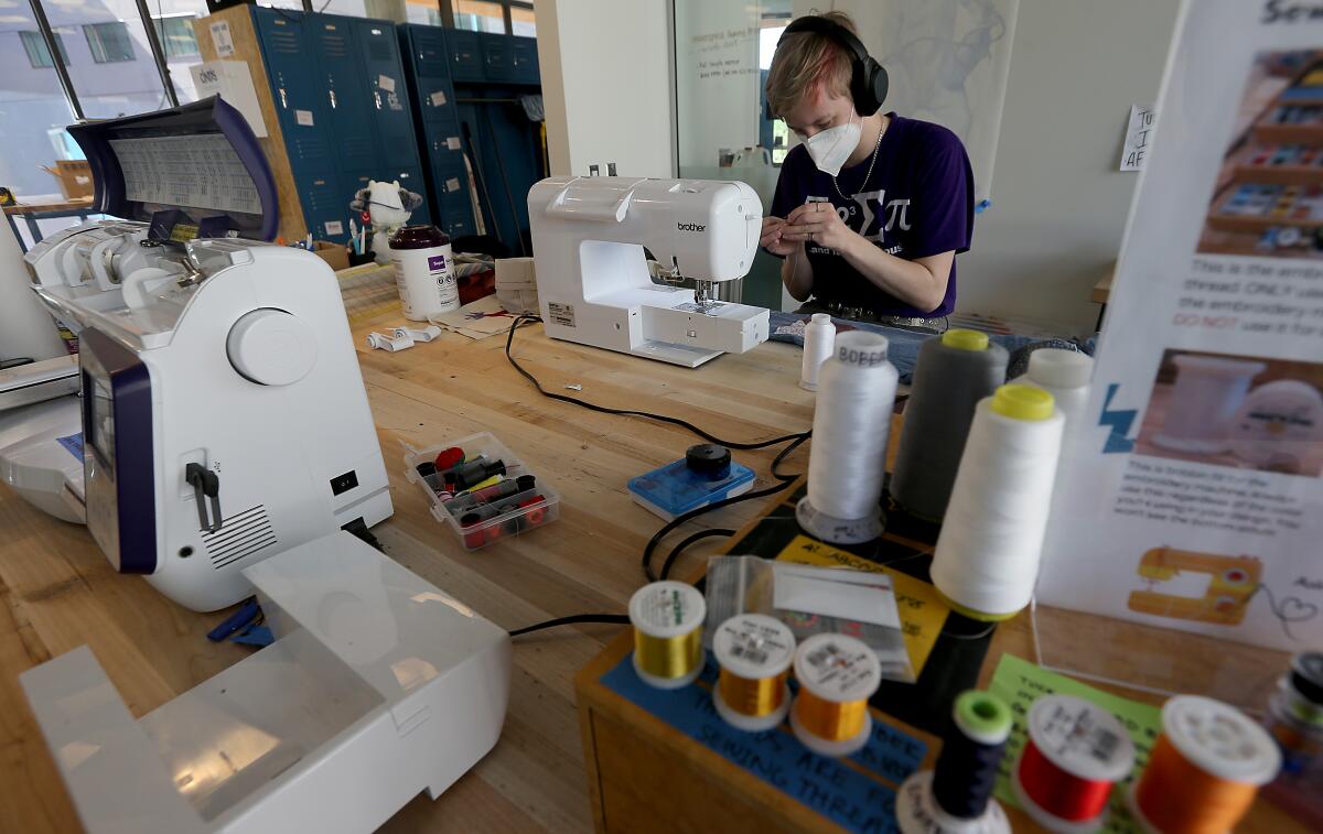A student uses a sewing machine in a craft room