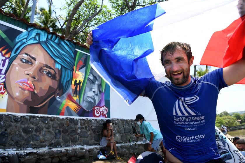 -SP-June 4, 2021: French surfer Joan Duru celebrates the gold in the Surf City El Salvador ISA World Surfing Games as he carried by a mural of fellow surfer Katherine Diaz, who was struck and killed by lightning a few months ago. (Wally Skalij / Los Angeles Times)