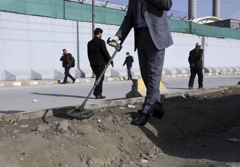 An Afghan security official looks for mines or improvised explosive device with metal detector on a roadside during a trip organized by the police for The Associated Press, in Kabul, Afghanistan, March 17, 2021. Sticky bombs slapped onto cars trapped in Kabul’s chaotic traffic are the newest weapons terrorizing Afghans in the increasingly lawless nation. The surge of bombings comes as Washington searches for a responsible exit from decades of war. (AP Photo/Rahmat Gul)