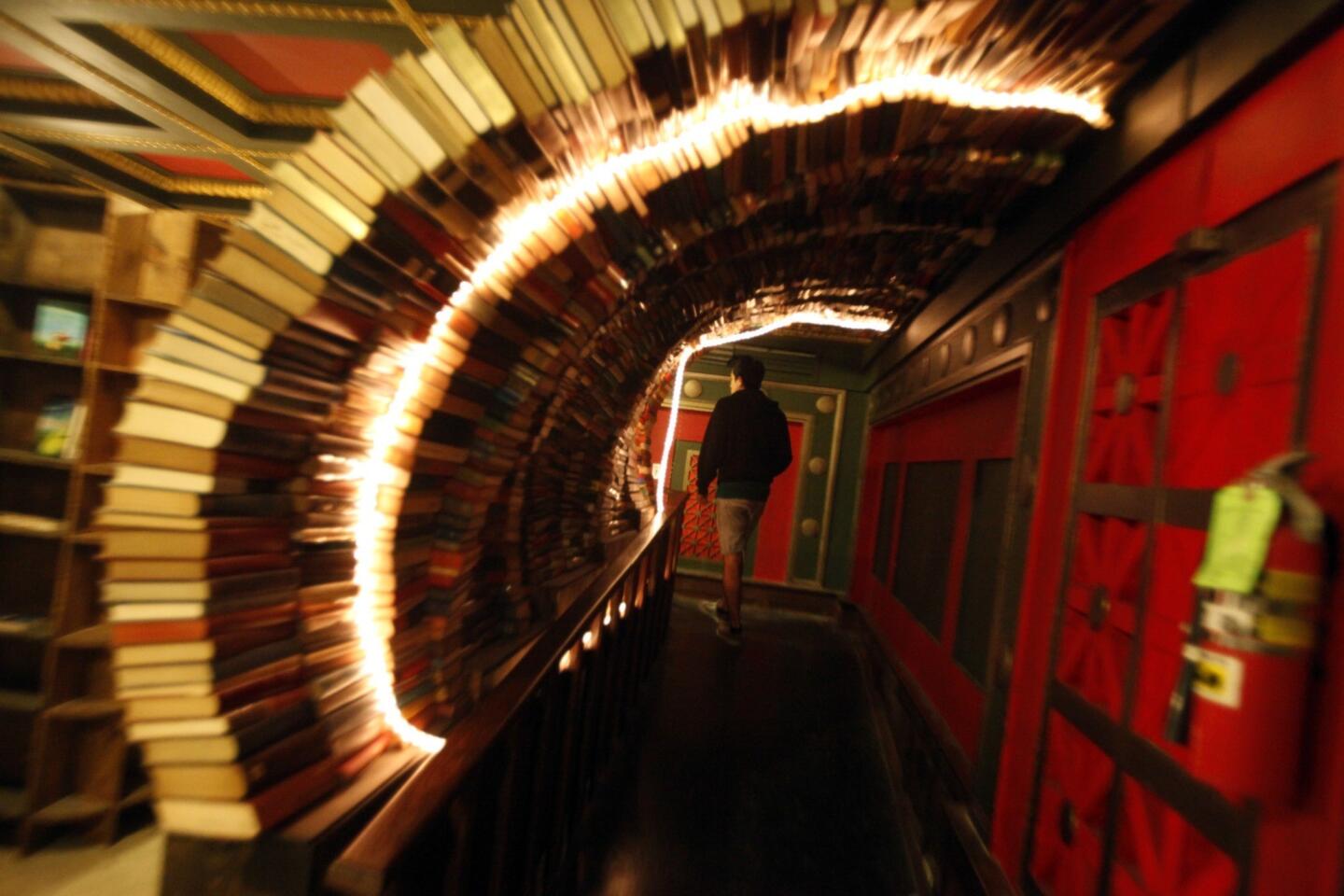 A visitor walks through a tunnel of books in the Labyrinth on the second floor of the Last Bookstore in downtown Los Angeles. The Labyrinth features a massive, chaotic, maze-like space housing more than 100,000 used books, all at $1 each. It features doors that lead nowhere, time-travel portholes looking into an artist's rendition of outer space, and "secret passage ways" leading into hidden book rooms.