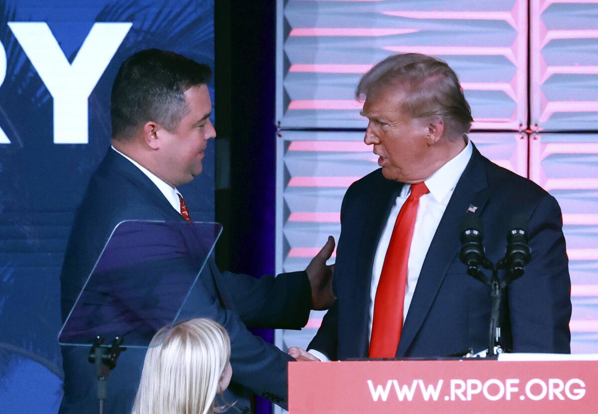 Two men in suits shake hands. 