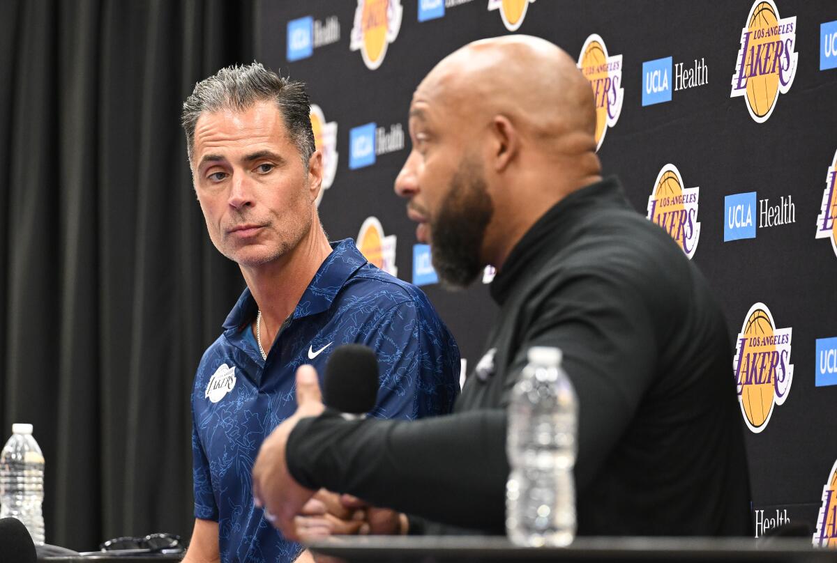 Lakers general manager Rob Pelinka, left, listens to coach Marvin Ham speak during a news conference.