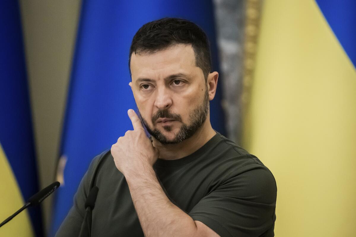 Ukrainian President Volodymyr Zelensky stands in front of his nation's flags.