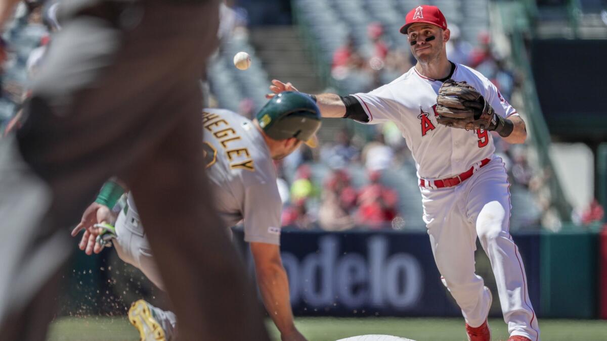 Angels second baseman Tommy La Stella turns a double play in front of Oakland's Josh Phegley during the fourth inning of the Angels' loss on Sunday.