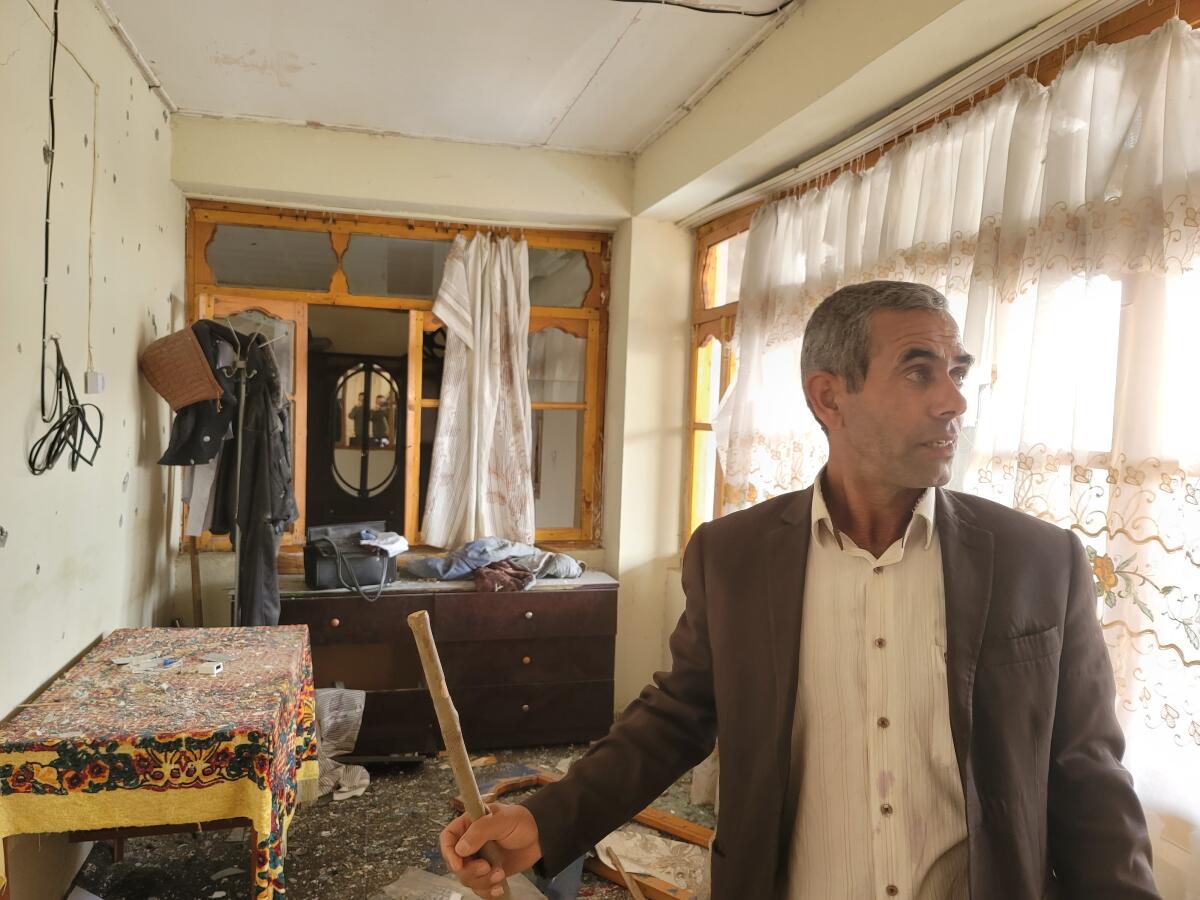Firidun Kadimov clears debris from inside his home after it was struck by a missile in Tezekend, Azerbaijan