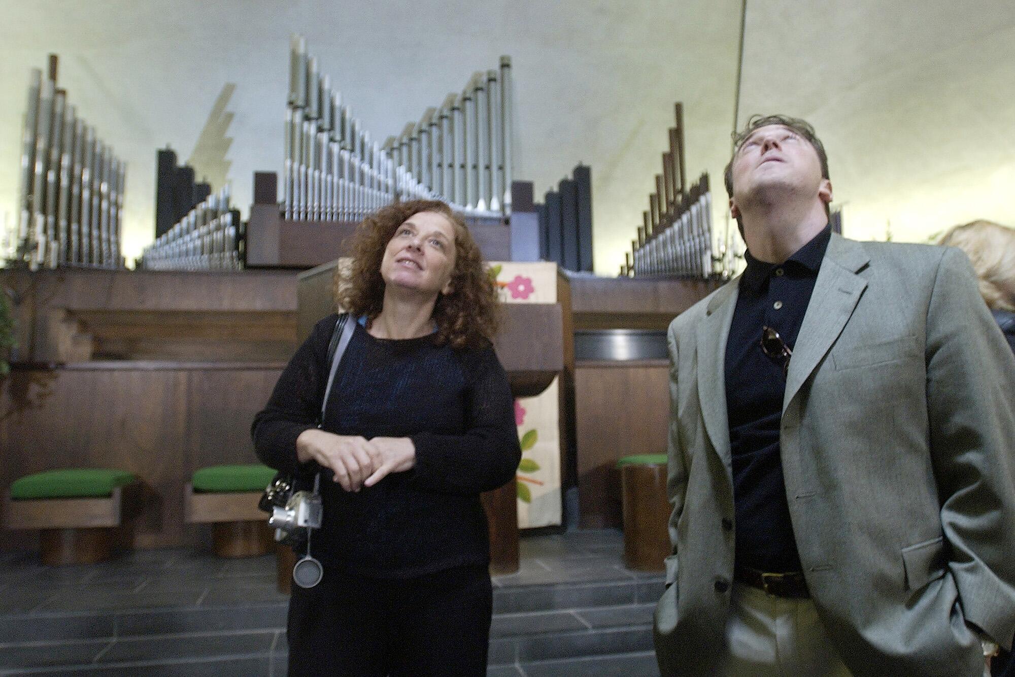 Two people, organ pipes jutting up at various angles behind them, admire the interior of Columbus' North Christian Church.