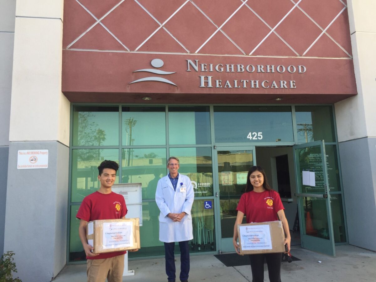 Casey Mariano (left) and Cady Mariano (right) deliver a donation of masks to Dr. Jim Schultz (center) at Neighborhood Healthcare in Escondido.
