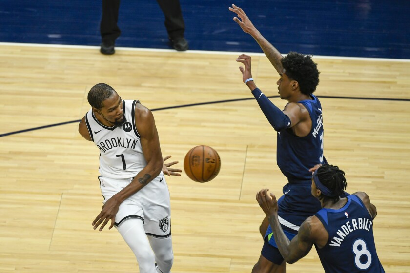 Brooklyn Nets forward Kevin Durant (7) passes the ball behind his back and around Minnesota Timberwolves forward Jaden McDaniels (3) and Timberwolves forward Jarred Vanderbilt (8) during the first half of an NBA basketball game Tuesday, April 13, 2021, in Minneapolis. (AP Photo/Craig Lassig)