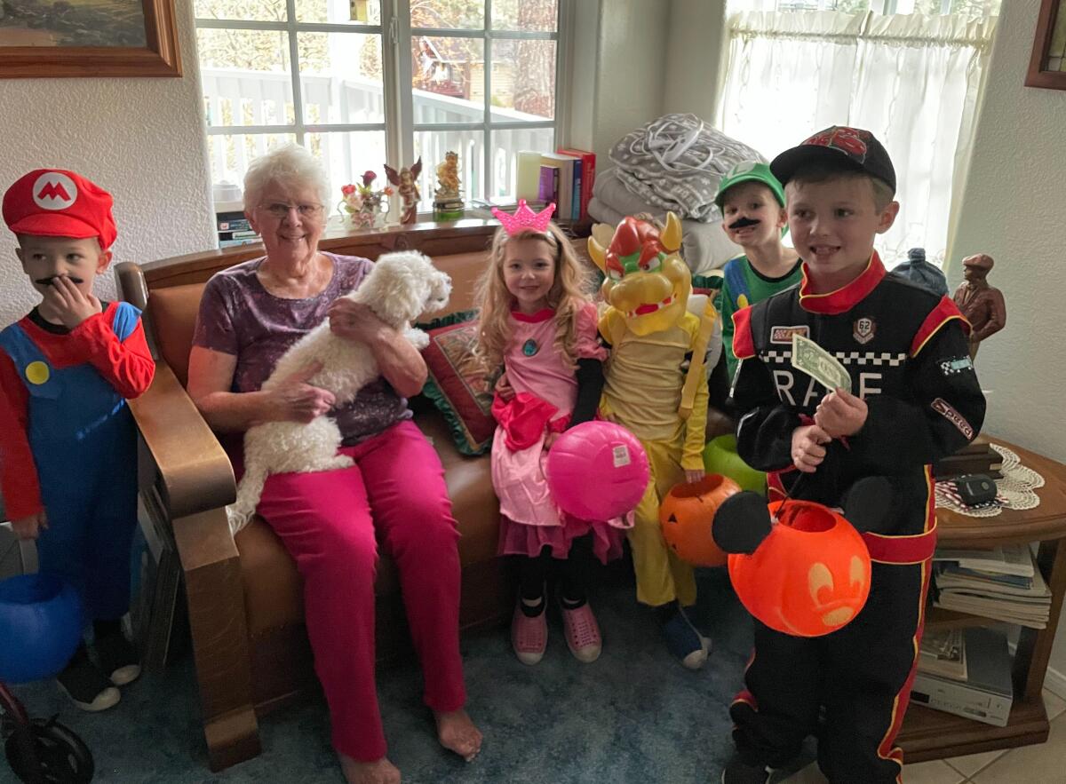 Five children in Halloween costumes visit a woman with a dog on her lap.