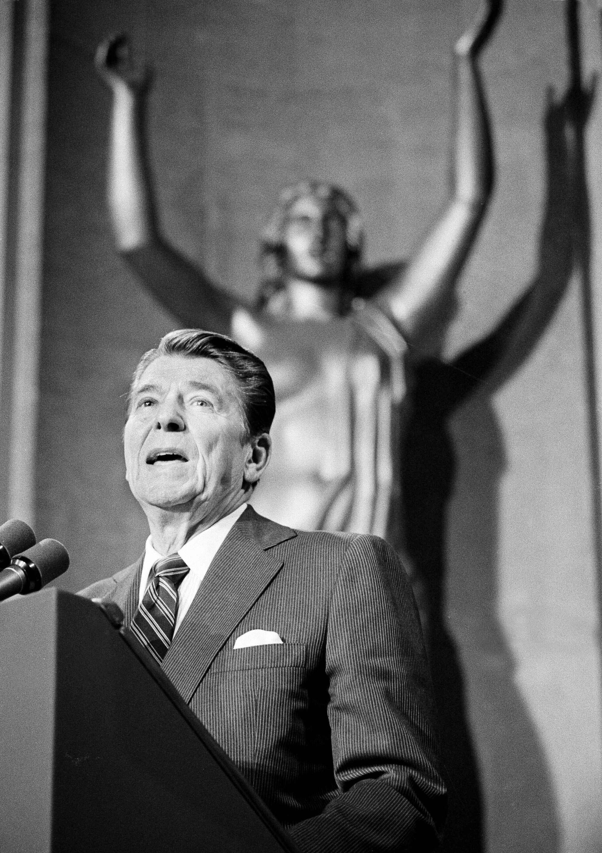 In a vintage black-and-white image, Ronald Reagan is seen standing at a podium before the scales of justice.