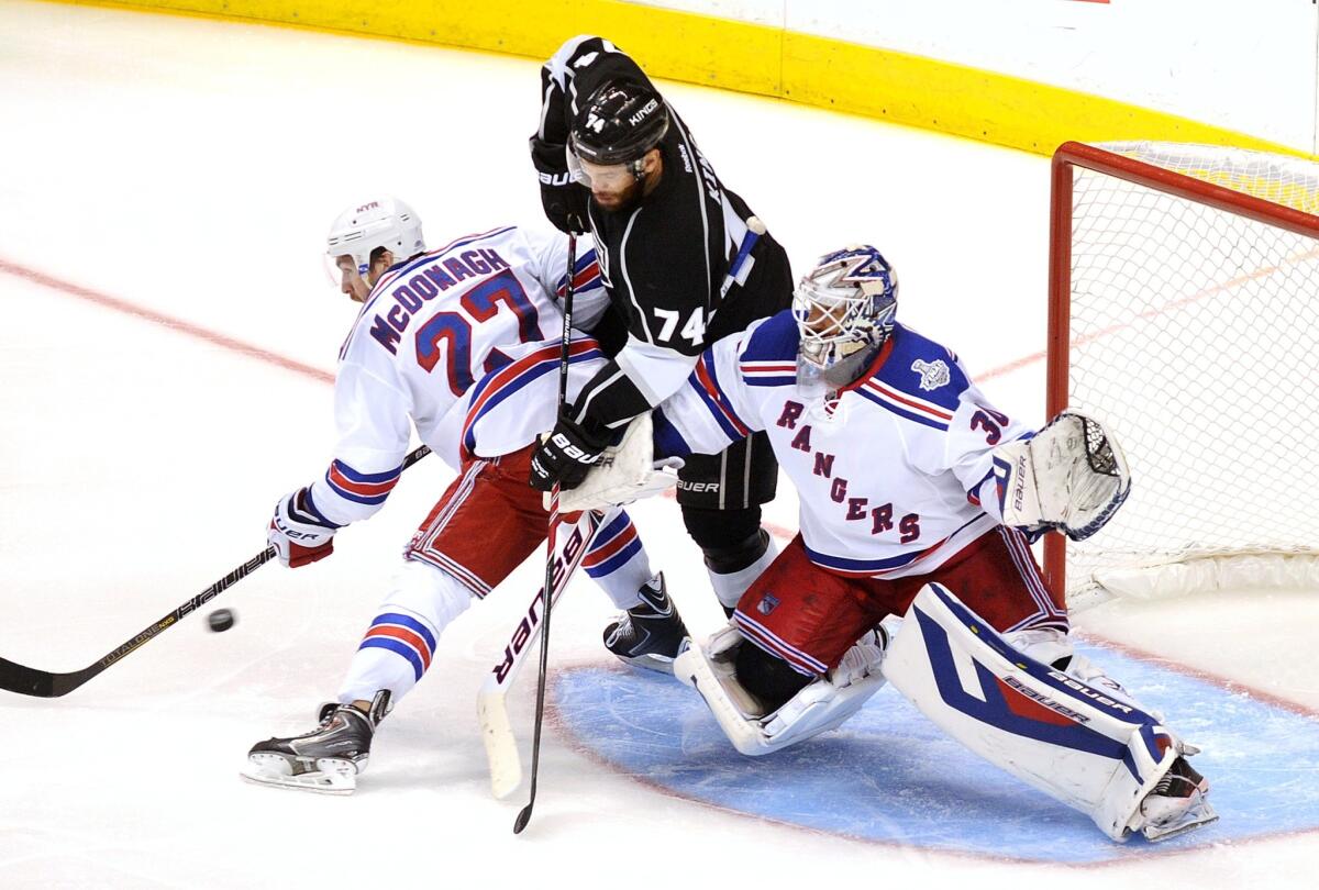 Kings forward Dwight King works in the crease between Rangers defenseman Ryan McDonagh and goaltender Henrik Lundqvist, deflecting a shot by teammate Matt Greene (not pictured) into the goal to cut the deficit to 4-3 in the third period.