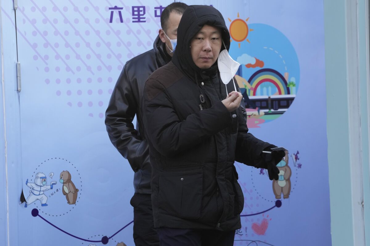 A resident pulls away a mask during COVID test in Beijing, Wednesday, Dec. 7, 2022. In a sharp reversal, China has announced a series of measures rolling back some of the most draconian anti-COVID-19 restrictions. (AP Photo/Ng Han Guan)