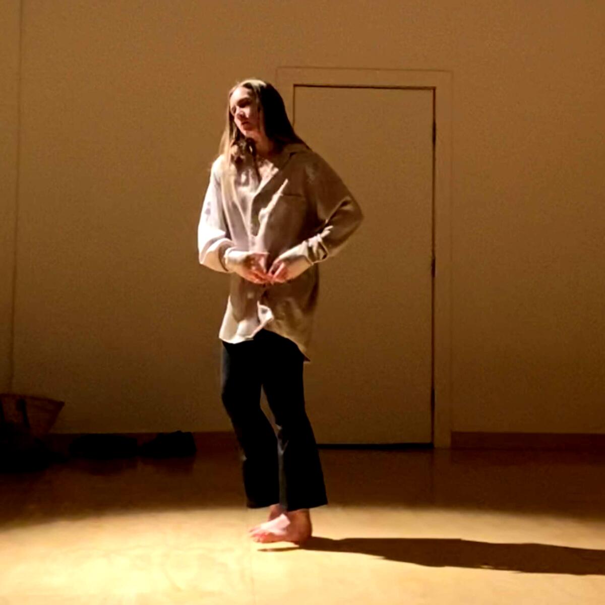 A woman standing in the middle of a dance studio.