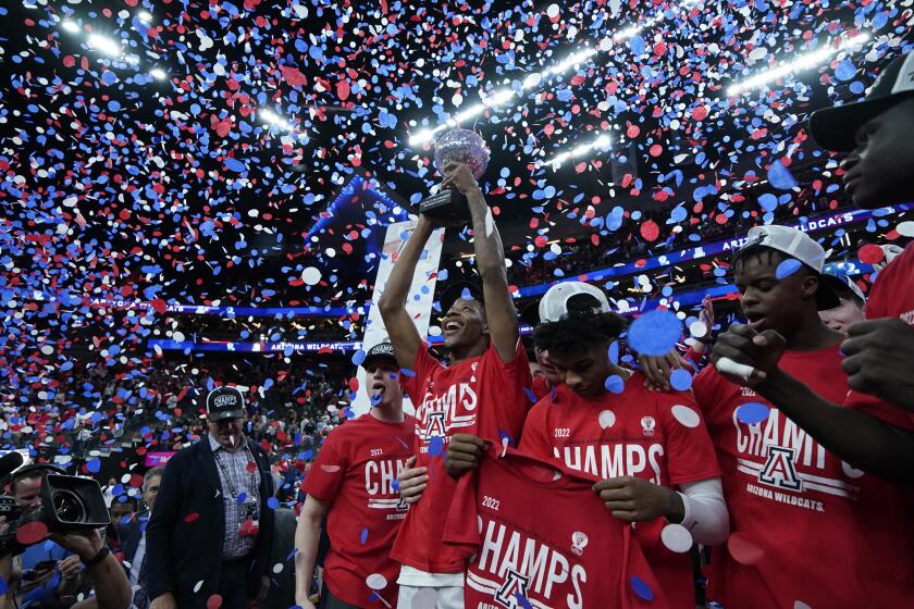 Arizona players celebrate with the trophy after defeating UCLA.