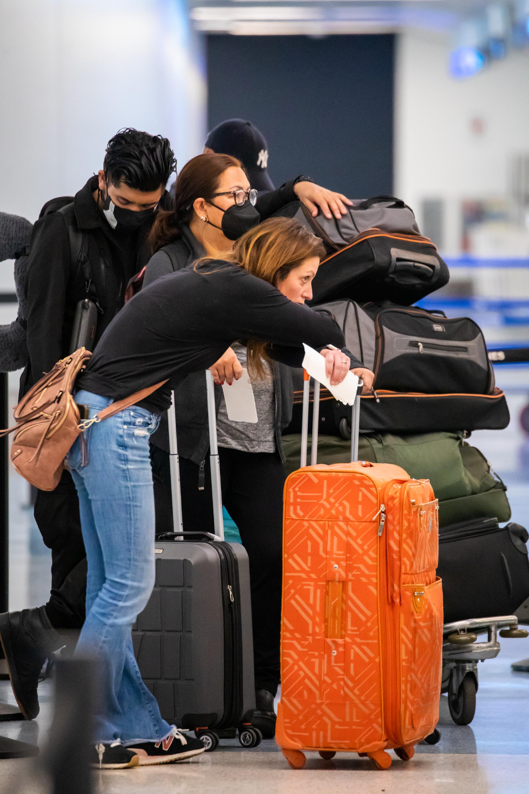 A woman waits in line with her luggage at an airport.