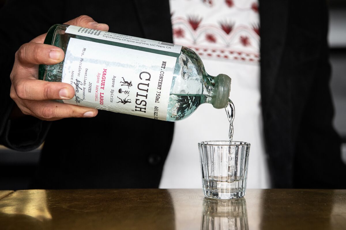 A man pours mezcal into a glass.
