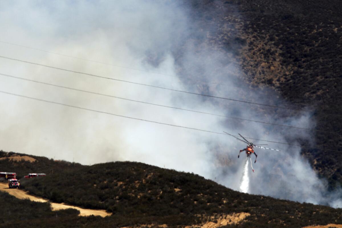 An Orange County Fire Authority helicopter makes a water drop on the Baker Fire near Santiago Canyon Road on Sunday.