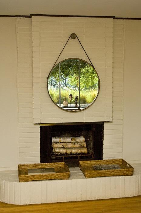 Though the designer confesses that his desk at work is often "controlled chaos," he prefers to come home to a relaxed, "organized look." Here, a mirror hung above the fireplace helps to bring a bit of the outdoors inside. New French doors on either side of his living room fireplace open onto the frontyard, now enclosed for privacy, graced with a koi pond and replanted with Pride of Madeira, agave and rosemary.