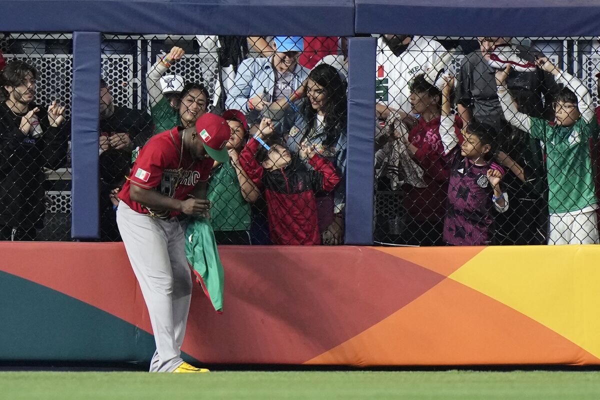Mexico left fielder Randy Arozarena (56) signs autographs on the warning track during a pitching change in the seventh inning of a World Baseball Classic game against Japan, Monday, March 20, 2023, in Miami. (AP Photo/Wilfredo Lee)