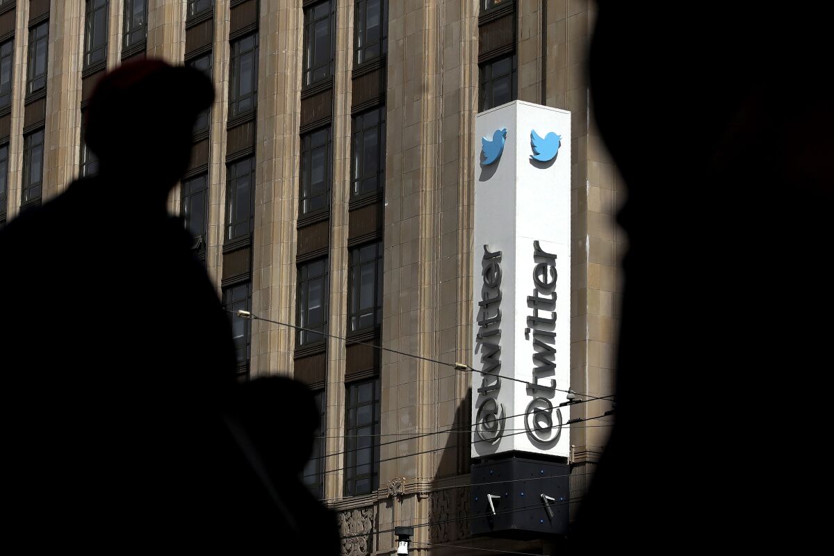 Shadows of pedestrians walking across the street from the Twitter office building in San Francisco