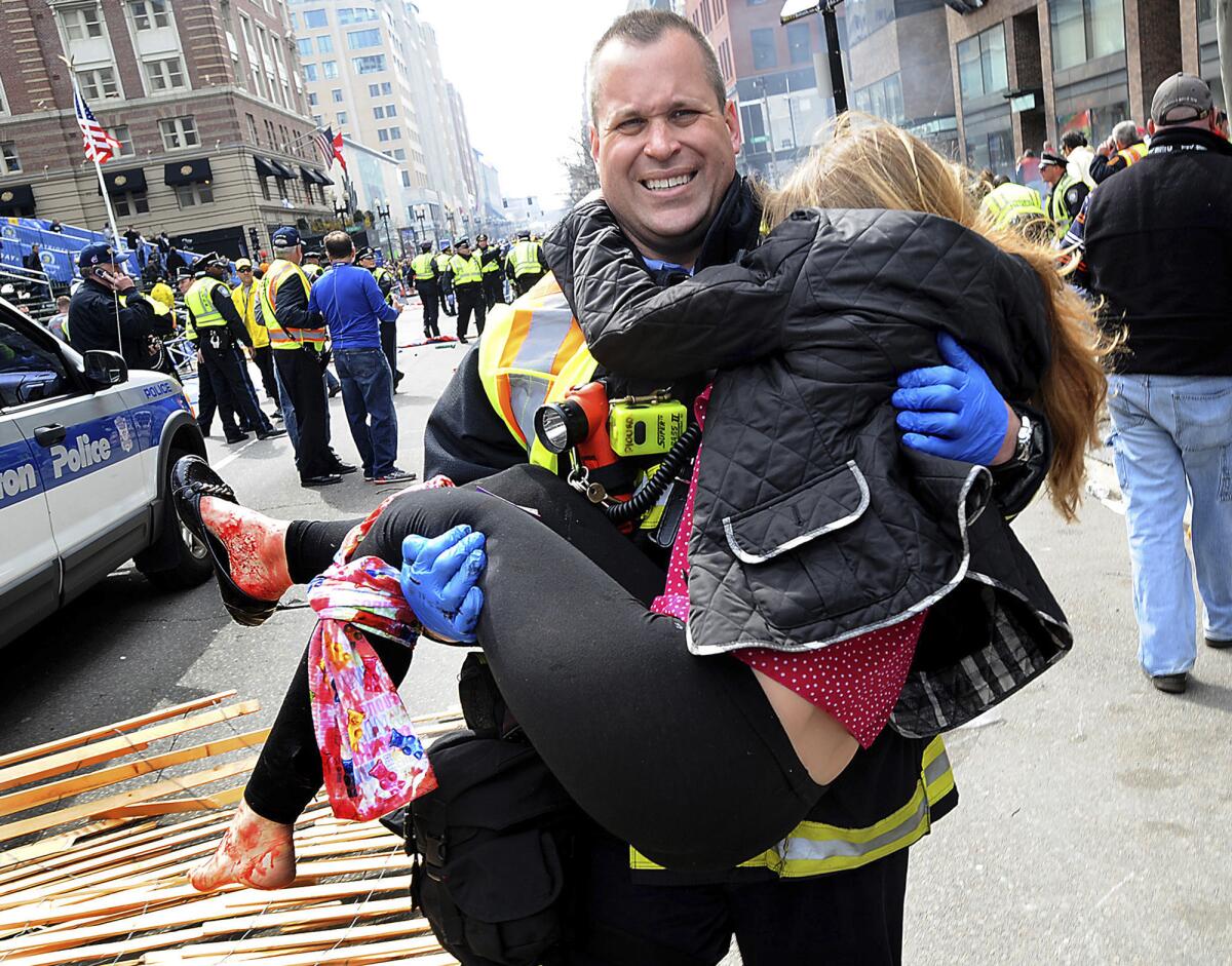 Firefighter James Plourde carries an injured girl away from the scene after the bombings near the finish line of the Boston Marathon.