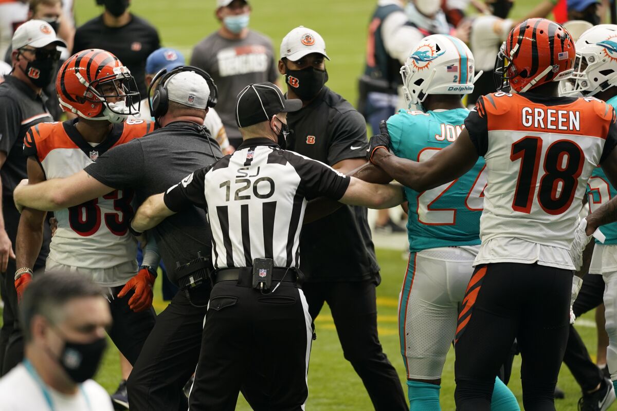NFL side judge Jonah Monroe (120) and Cincinnati Bengals coaches attempts to stop a fight on the field during the first half of an NFL football game against the Miami Dolphins, Sunday, Dec. 6, 2020, in Miami Gardens, Fla. Cincinnati Bengals wide receiver Tyler Boyd (83) was disqualified for unnecessary roughness. (AP Photo/Lynne Sladky)
