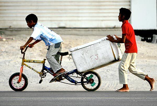 Boys sell fish door-to-door in Jannusan, Bahrain, shortly before the day's fasting ends with the evening meal for Muslims during the holy month of Ramadan.
