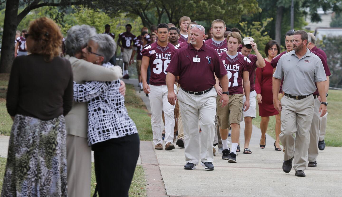 Members of the Salem High school football team arrive to remember alumnus WDBJ-TV7 cameraman Adam Ward, as mourners hug at Salem High School in Salem, Va., on Aug. 31, 2015.