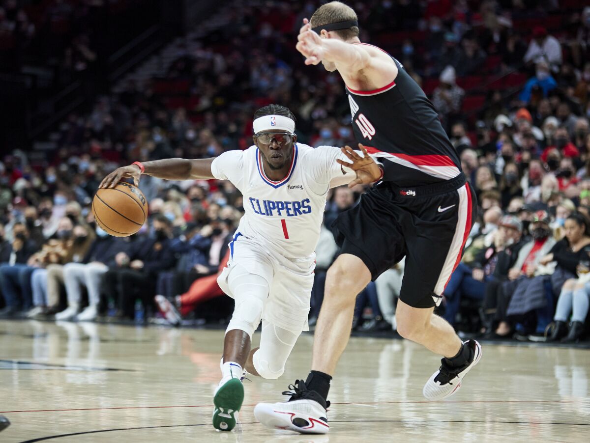 Los Angeles Clippers guard Reggie Jackson, left, dribbles around Portland Trail Blazers center Cody Zeller during the first half of an NBA basketball game in Portland, Ore., Monday, Dec. 6, 2021. (AP Photo/Craig Mitchelldyer)