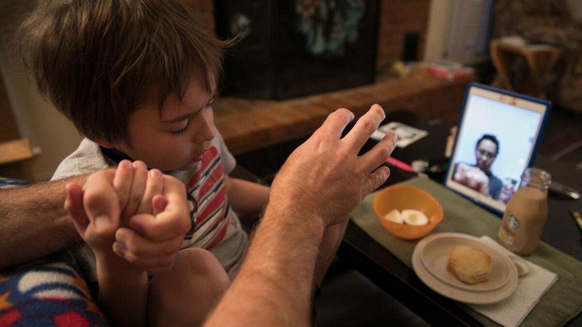 Jason and Ashton Rochester pray over their breakfast as they FaceTime with Cecilia in Mexico.