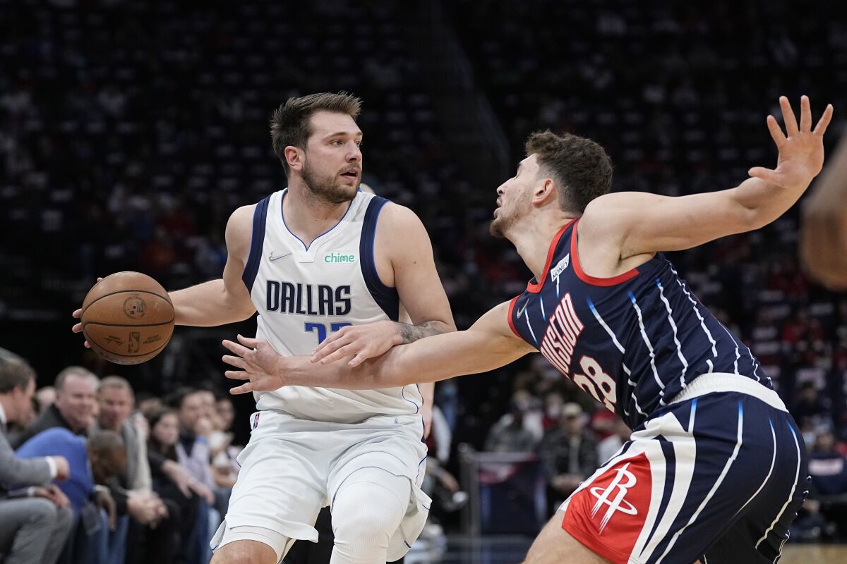 Houston Rockets' Alperen Sengun (28) tries to steal the ball from Dallas Mavericks' Luka Doncic (77) during the first half of an NBA basketball game Friday, March 11, 2022, in Houston. (AP Photo/David J. Phillip)