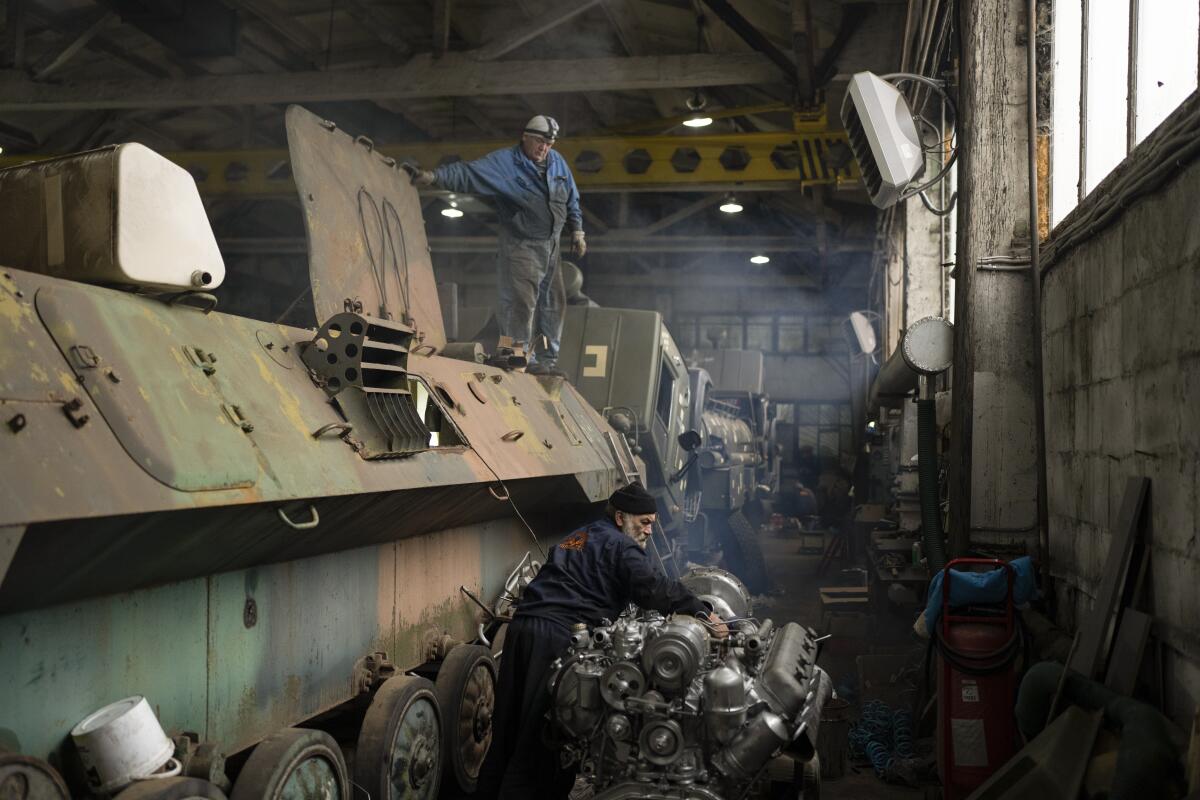 A mechanic repairs an engine of an armored personnel carrier