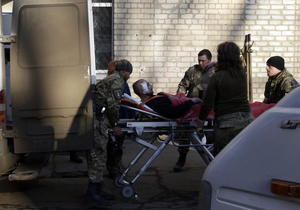 Ukrainian troops load an injured man into an ambulance in the eastern Ukrainian city of Artemivsk on Friday. At least 25 people died and dozens were injured in intensified fighting a day after a new cease-fire was signed.