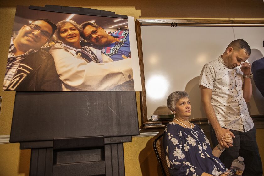 CORONA, CA-AUGUST 26, 2019: Paola French and her son Kevin react as Attorney Dale Galipo addresses the media during a press conference at the Ayres Hotel in Corona to announce plans to file a civil claim against the city of Los Angeles and LAPD officer Salvador Sanchez for the shooting death of PaolaÕs son, Kenneth French inside a Corona Costco earlier this year. Photograph at left is of from left to right-Kenneth French and his parents, Paola, and Russell, taken in 2019. (Mel Melcon/Los Angeles Times)