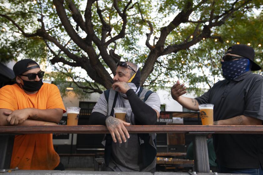 LOS ANGELES, CA - JUNE 30: Adan Gutierrez, left, Ramon Ayala, middle, and Vicente Fernandez, right, enjoy a beer outside the Central Market during the evening on Tuesday, June 30, 2020 in Los Angeles, CA. They were all wearing masks and keeping a distance for one another. Inside the brewery remains open because they also sell food. Citing the rapid pace of coronavirus spread in some parts of California, Gov. Gavin Newsom ordered seven counties including Los Angeles on Sunday to immediately close any bars and nightspots that are open and recommended eight other counties take action on their own to close those businesses. (Francine Orr / Los Angeles Times)