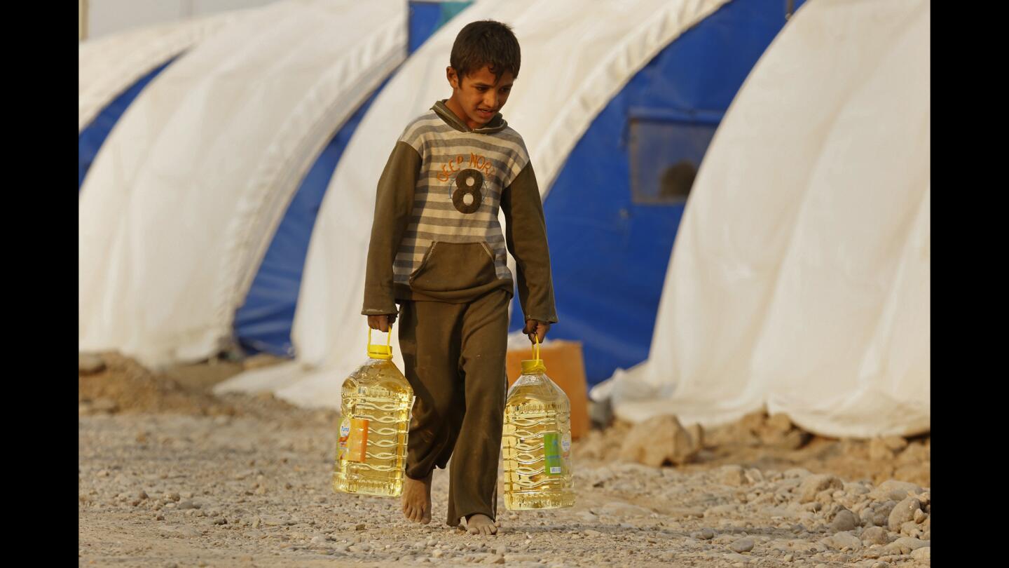 An Iraqi boy, newly arrived at a camp for the displaced, carries food provided by the World Food Program.