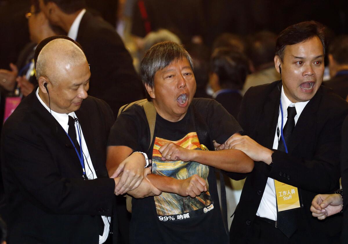 Pro-democracy lawmaker Lee Cheuk-yan, center, is taken away by security guards after a protest against Li Fei, deputy secretary general of China's National People's Congress standing committee, in Hong Kong on Monday.